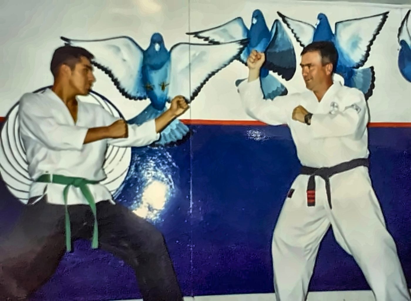 Práctica de combate con su maestro frente al mural de palomas